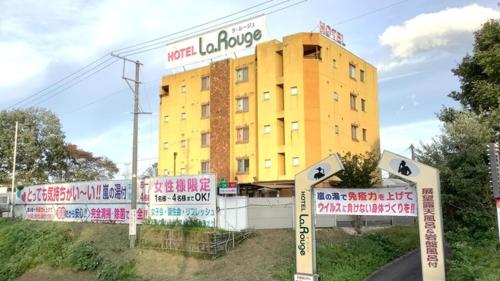 ein gelbes Gebäude mit Schildern davor in der Unterkunft Hotel La Rouge - Vacation STAY 89068v in Fukushima