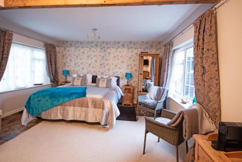 a bedroom with a bed and a chair and windows at Magpies Lodge in Slinfold