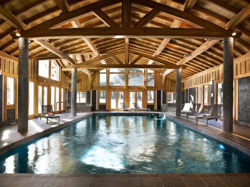 een zwembad in een gebouw met een houten plafond bij CGH Résidences & Spas Le Hameau De Pierre Blanche in Les Houches