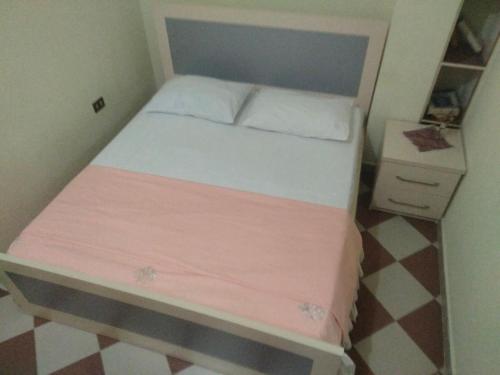 a small bedroom with a bed with a pink blanket at Apartment in Vlorë