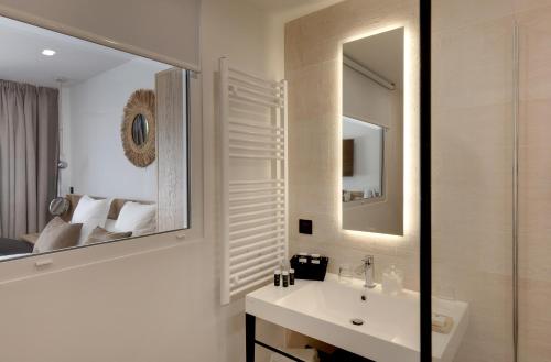 a bathroom with a sink and a mirror and a bed at Vila De La Mar & Spa in Saintes-Maries-de-la-Mer