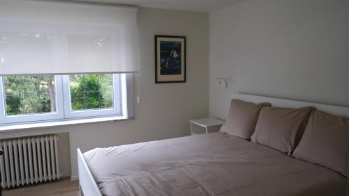 a white bedroom with a bed and two windows at Villa Le Renard in Knokke-Heist