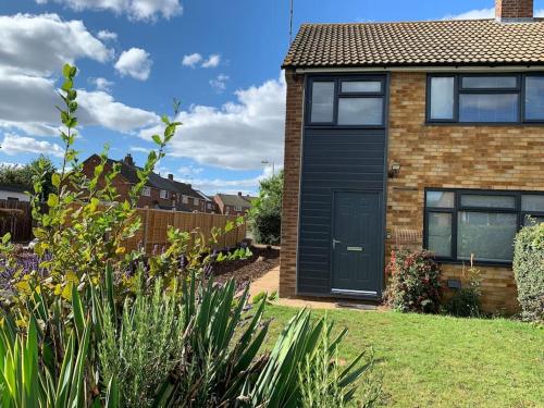 a house with a black door in a yard at Fabulous 4 bed 4 bath right by Luton Airport in Luton