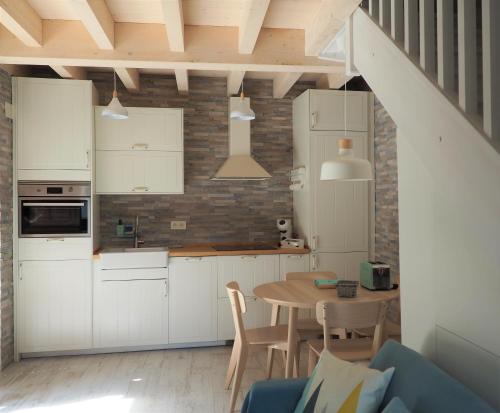 a kitchen with white cabinets and a wooden table at Casa gueli in Cangas de Onís