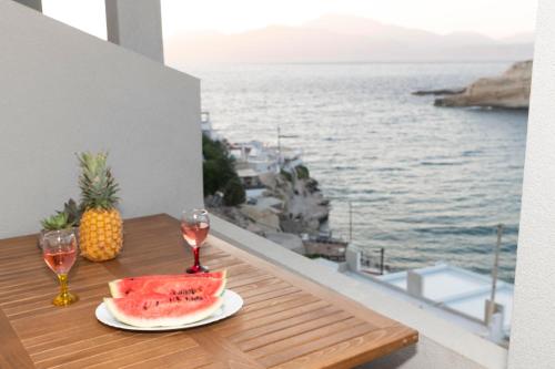 a table with a slice of watermelon and two glasses of wine at Emmanouela Apartment in Matala