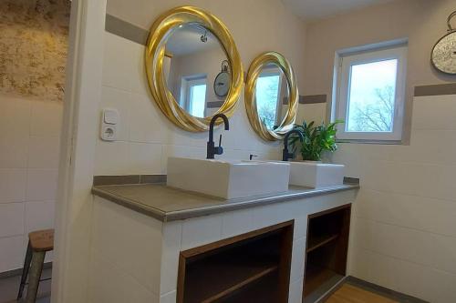 ein Bad mit einem Waschbecken und 2 Spiegeln in der Unterkunft Auszeit auf dem Drachenhof, das Hyggehaus in Plattenburg