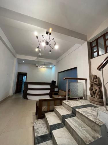 a living room with stairs and a chandelier at Hotel YSM Grand in Tezpur