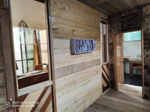 La salle de bains est pourvue d'un mur en bois et d'un miroir. dans l'établissement Naam house, à SantʼAna