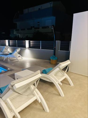 two white chairs and a table with a vacuum at Flev's Luxury House with pool in Kremasti