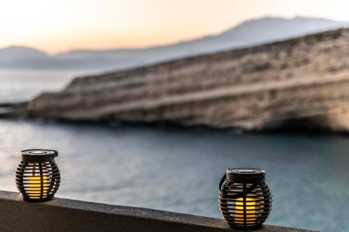 two black and yellow vases sitting on a ledge near the water at Georgia Apartment in Matala