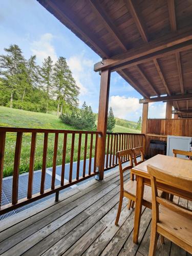 a porch of a cabin with a table and chairs at Hostdomus - Sansicario R21 in Cesana Torinese