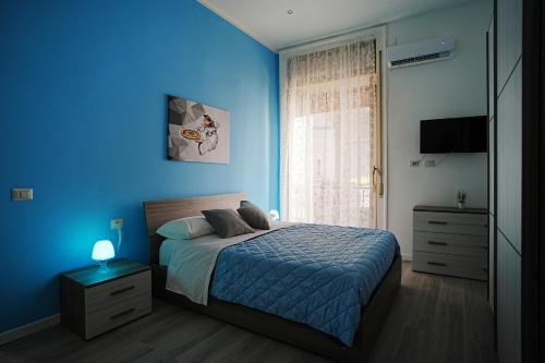 een blauwe slaapkamer met een bed en een raam bij Just Like Home in Napels