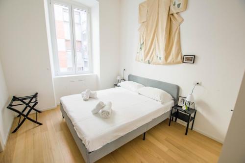 um quarto com uma cama com lençóis brancos e uma janela em Casa Imperatrice Sissi em Trieste