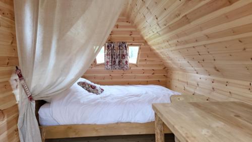 a bedroom in a log cabin with a bed and a table at Les Cabanes Flottantes in Givrauval