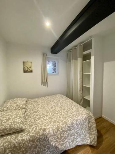 um pequeno quarto com uma cama e uma janela em Le petit beauregard em Le Fenouiller