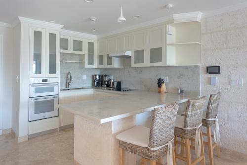 a kitchen with white cabinets and a island with bar stools at The Crane Resort in Saint Philip