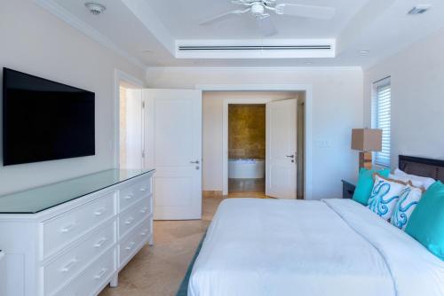 a white bedroom with a bed and a flat screen tv at The Crane Resort in Saint Philip
