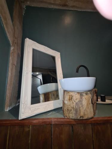 einen Spiegel und ein Waschbecken auf einem Holztisch in der Unterkunft Chateau Humieres Coach House in Humières