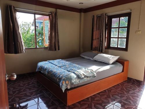 Tommy Resort Koh Tao في كو تاو: غرفة نوم بسرير في غرفة بها نافذتين