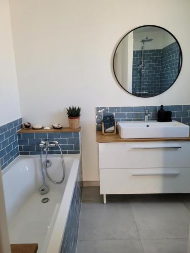 uma casa de banho com uma banheira, um lavatório e um espelho. em Maison Gioia em Châteaurenard