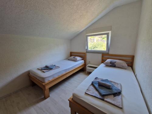 two beds in a small room with a window at Sweet guesthouse in Mostar