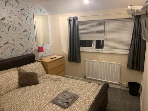 a small bedroom with a bed and a window at Superb 4 Bed 4 Bath House Right by Luton Airport in Luton