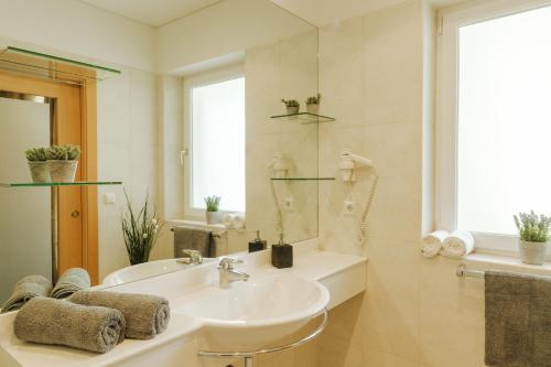 La salle de bains blanche est pourvue d'un lavabo et d'un miroir. dans l'établissement Hotel Elisabeth, à Merano