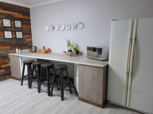a kitchen with a counter with stools and a refrigerator at Mossie Nes - Self Catering in Bloemfontein