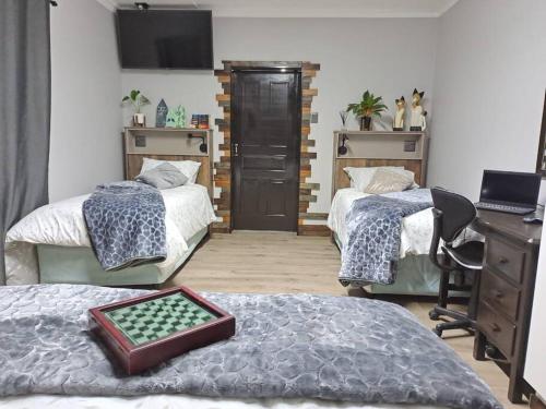1 dormitorio con 2 camas, escritorio y escritorio en Mossie Nes - Self Catering, en Bloemfontein