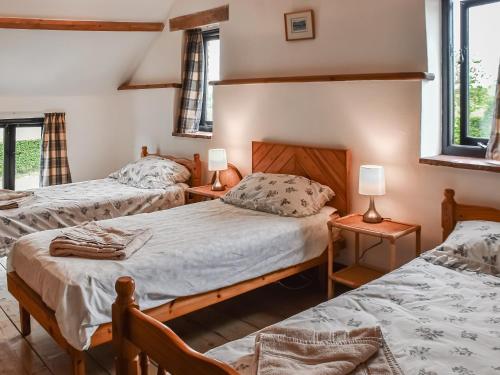 a bedroom with two beds and two lamps and windows at Oak Barn in Felbrigg