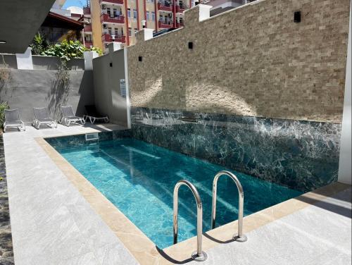 a swimming pool next to a brick wall with chairs around it at New apartment by Cleopatra in Alanya