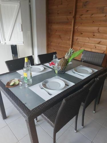 una mesa con platos y una piña encima en Beau T2 Cosy tout Confort avec terrasse et jardin, en Les Abymes