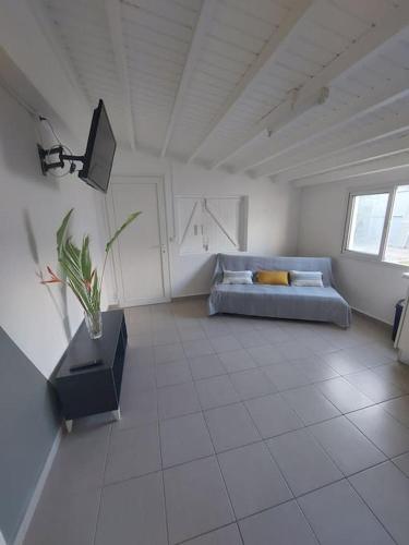 Habitación blanca grande con cama y TV. en Beau T2 Cosy tout Confort avec terrasse et jardin, en Les Abymes