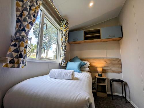 - une petite chambre avec un lit et une fenêtre dans l'établissement Coed Helen Holiday Park, à Caernarfon