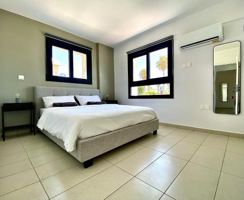 Sea La Vie #2 - Luxury Seaview apartment في بافوس: غرفة نوم بسرير كبير ونوافذ