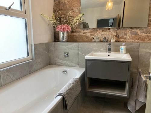 La salle de bains est pourvue d'une baignoire, d'un lavabo et d'une baignoire. dans l'établissement Sommersway Cottage, à Brixham