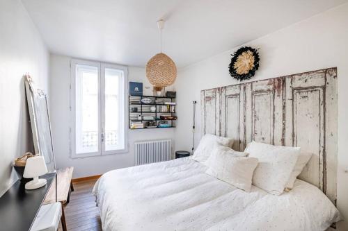 una camera con letto bianco e testiera in legno di Charmant Appartement avec Jardin a Suresnes