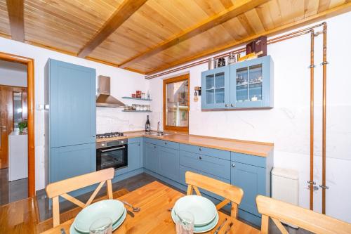 a kitchen with blue cabinets and wooden ceilings at House Andrija in Jasenak