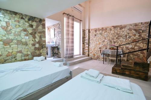 two beds in a room with a stone wall at Garden Villa Lake Side & Glamping in Ksamil