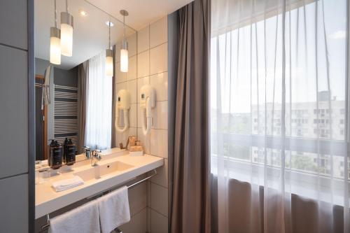 a bathroom with a sink and a large window at Mercure Warszawa Grand in Warsaw