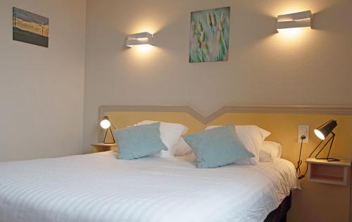 a bedroom with a large white bed with two blue pillows at Logis Restaurant & Hôtel À la 12 in Delme