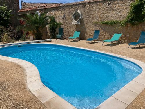 a large blue swimming pool with chairs in a yard at La Villa Celine in Saint-Laurent-de-la-Cabrerisse