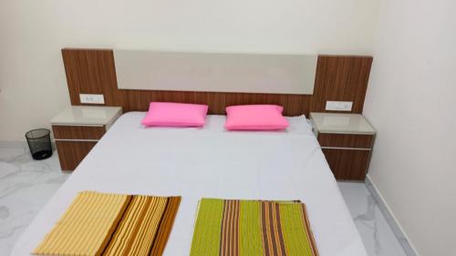 een bed met 2 roze kussens in een kamer bij SPN Shubam Rooms in Tirunelveli