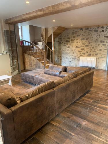 a large brown couch in a room with a stone wall at Gîte familial A la bonne heure in Chilhac