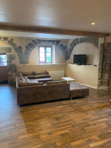 a large living room with a couch and a tv at Gîte familial A la bonne heure in Chilhac
