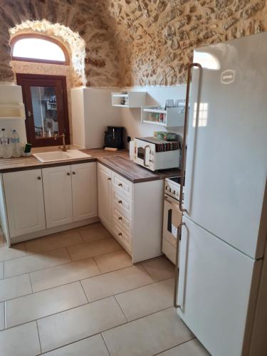 cocina con armarios blancos y nevera en Village home, en Chios