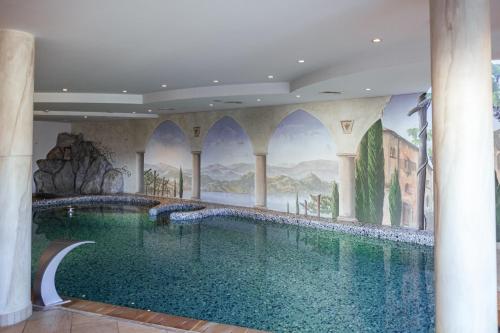 a swimming pool in a building with a painting on the wall at DAS BADL - Smart Retreat AO in Caldaro