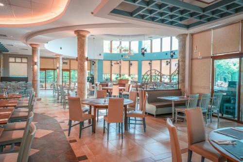 una sala da pranzo con tavoli, sedie e finestre di Calimera Ralitsa Superior Hotel - Ultra All Inclusive plus Aquapark ad Albena