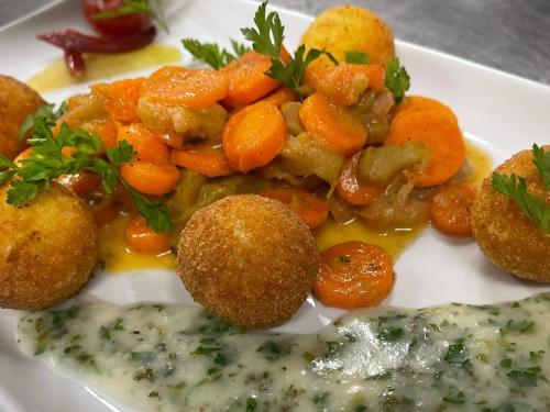 a white plate of food with carrots and gravy at Hotel Sonnenhügel in Bad Bevensen