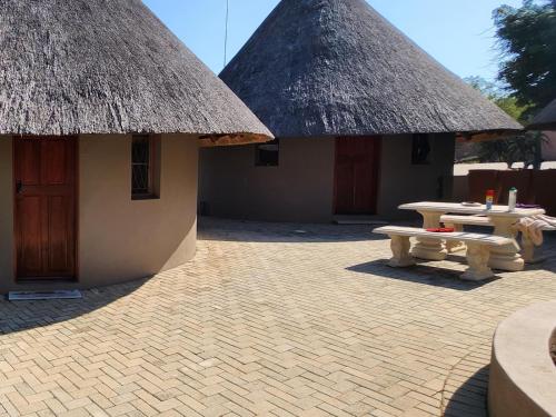 two huts with thatched roofs and a picnic table in front at Thandolwami Bushlodge & Spa in Hoedspruit